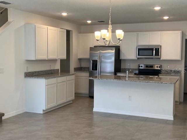 A kitchen features white cabinets, granite countertops, stainless steel appliances, and a central island — 642 BELGROVE STREET, DEBARY, FL
