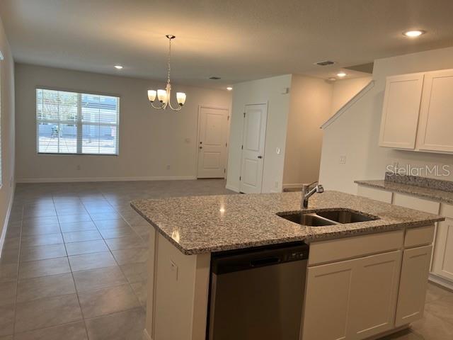 A kitchen island with a granite countertop and stainless steel dishwasher faces an open living area — 642 BELGROVE STREET, DEBARY, FL