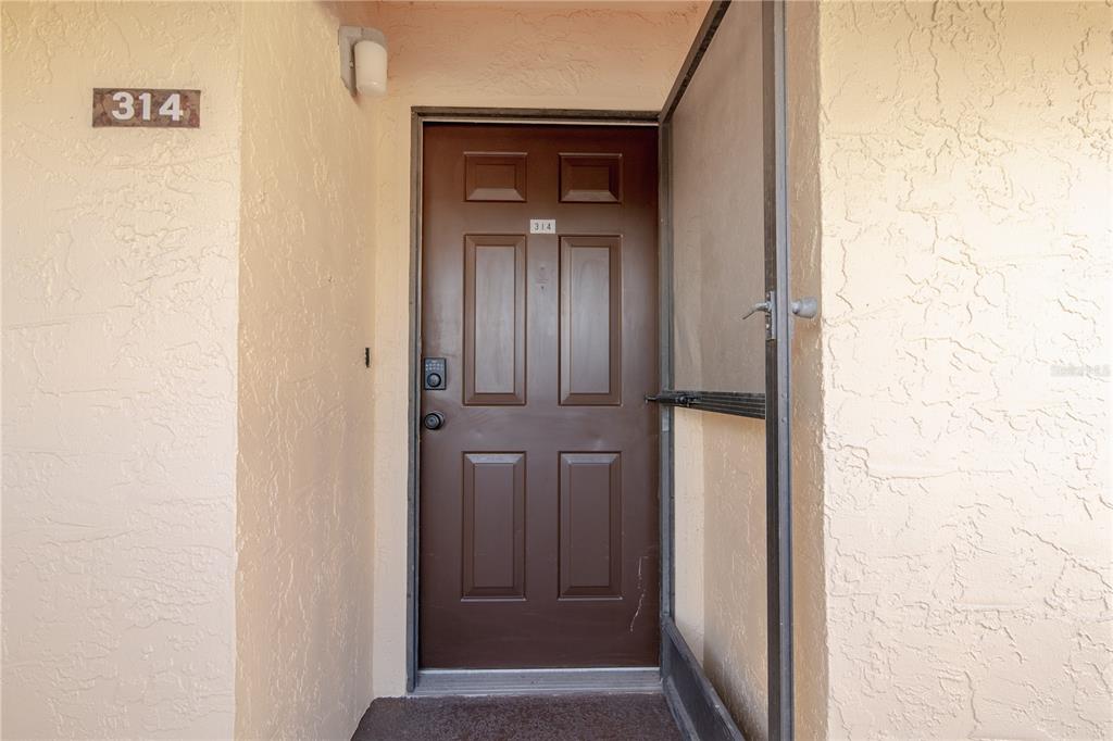 A brown front door with a screen door and the number 314 on the wall — 2395 HARBOR BOULEVARD UNIT 314, PORT CHARLOTTE, FL