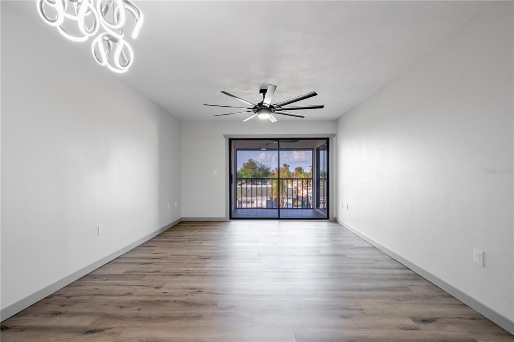 An empty room with wood-look flooring, a ceiling fan, and a sliding glass door — 2395 HARBOR BOULEVARD UNIT 314, PORT CHARLOTTE, FL