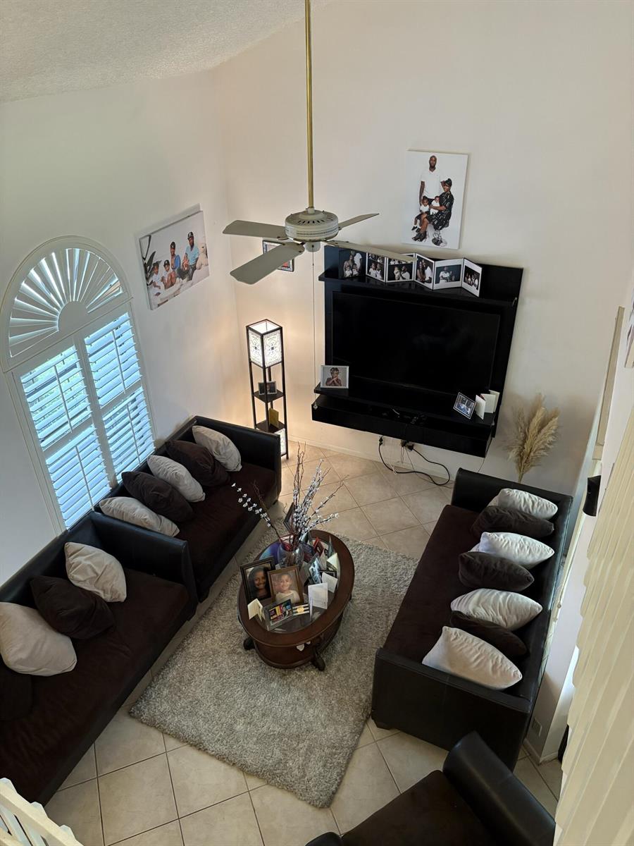 A high-angle view of a living room featuring dark sofas, a television, and tile flooring — 1750 NW 107th Way, Plantation FL 33322, PLANTATION, FL