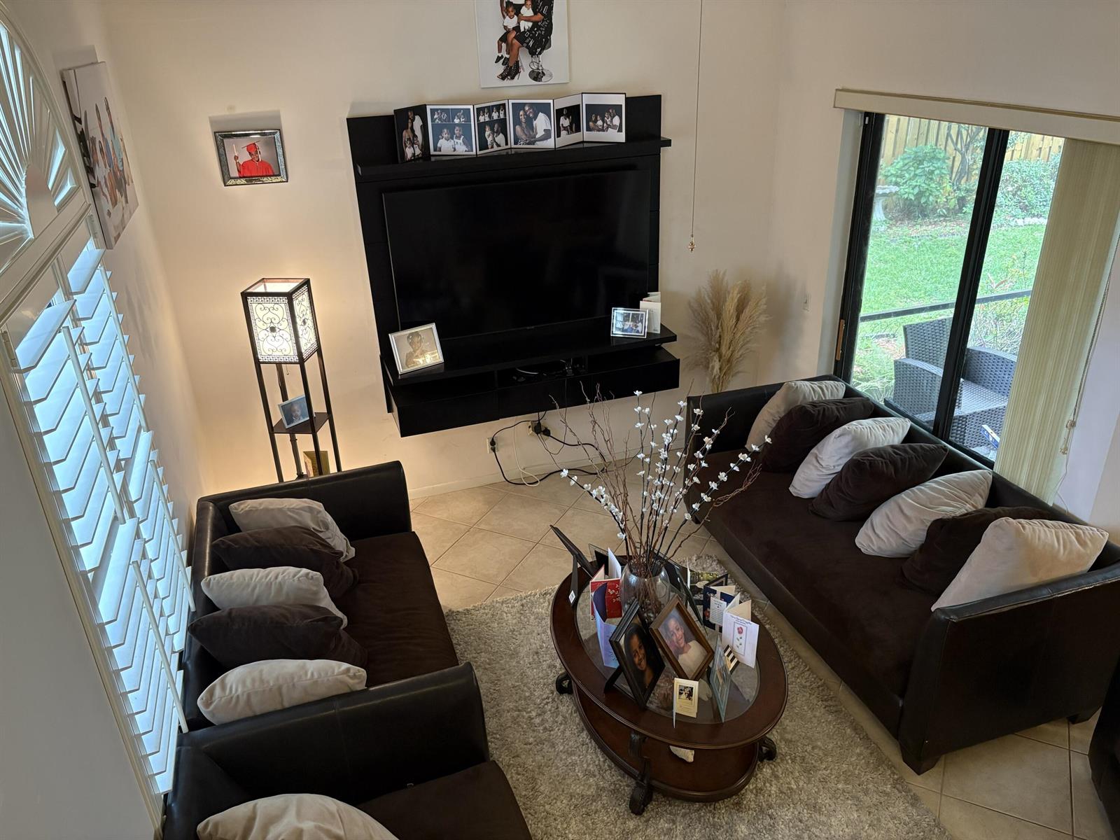 A living room features two dark brown sofas, a wall-mounted television, and a glass coffee table — 1750 NW 107th Way, Plantation FL 33322, PLANTATION, FL