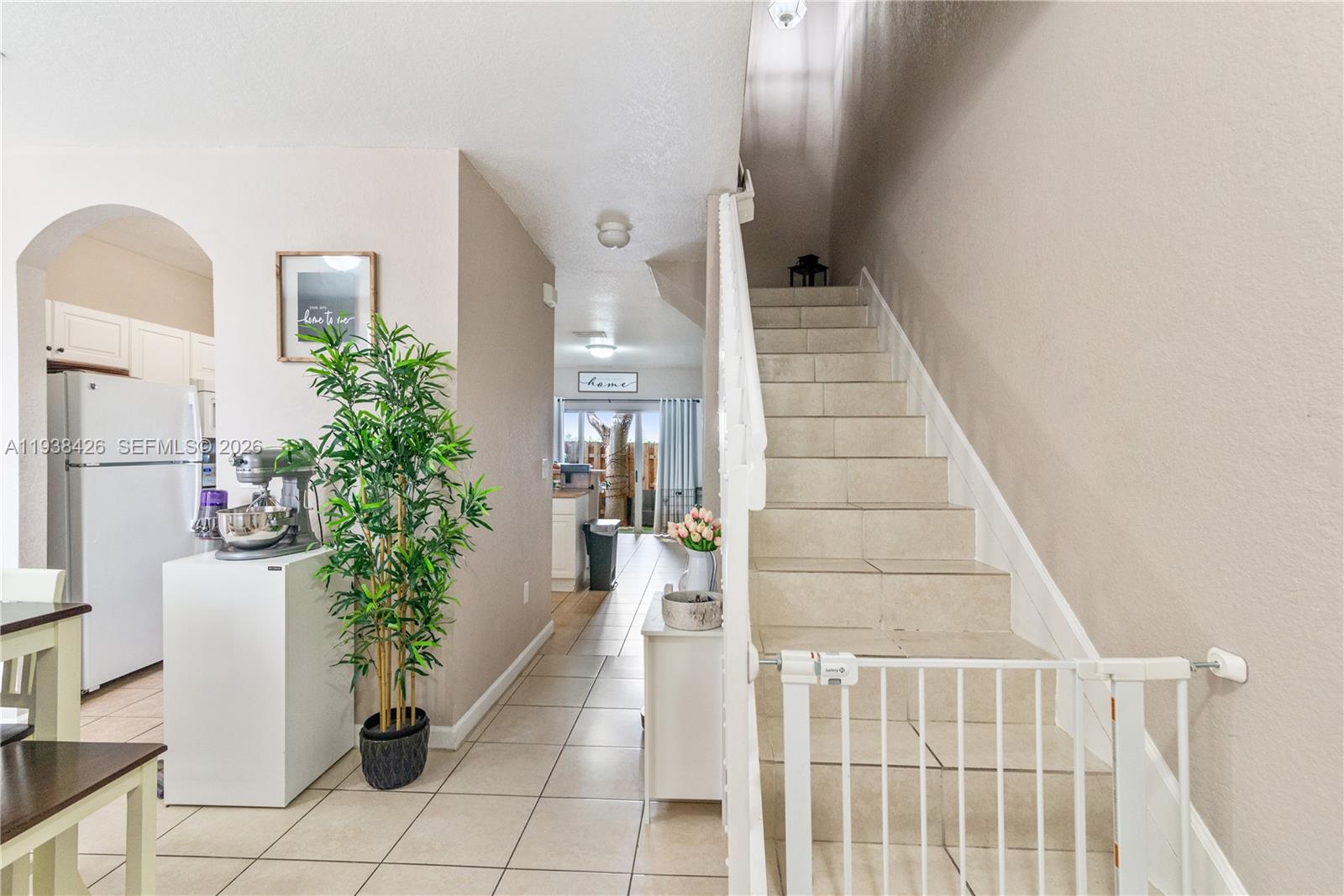 A tiled hallway leads to a kitchen, featuring a staircase with a safety gate — 1420 NE 33rd Ave # 15, Homestead FL 33033, HOMESTEAD, FL
