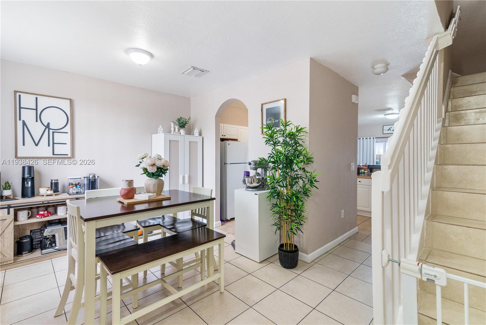 A dining area features a wooden table with benches, tile flooring, and a nearby staircase — 1420 NE 33rd Ave # 15, Homestead FL 33033, HOMESTEAD, FL