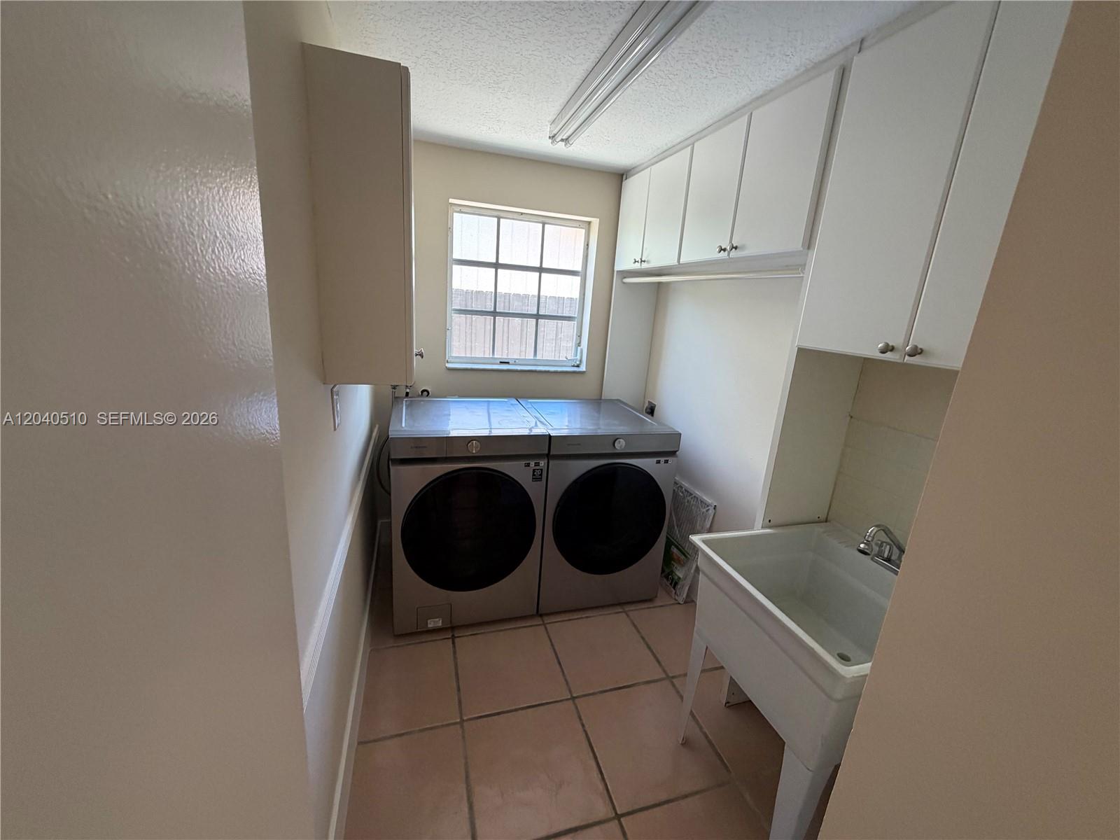 A laundry room features a utility sink, white cabinets, and stainless steel washer and dryer — 15836 SW 144th Pl, Miami FL 33177, MIAMI, FL
