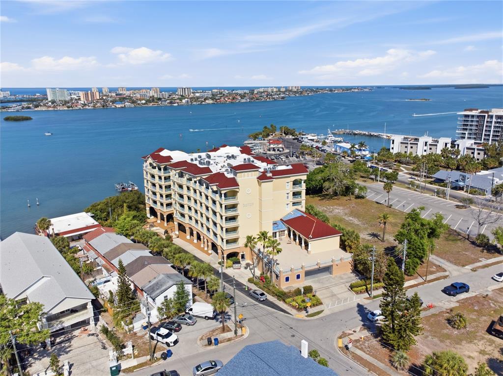 An aerial view shows a multi-story waterfront condominium building with a red roof — 700 N OSCEOLA AVENUE UNIT 305, CLEARWATER, FL