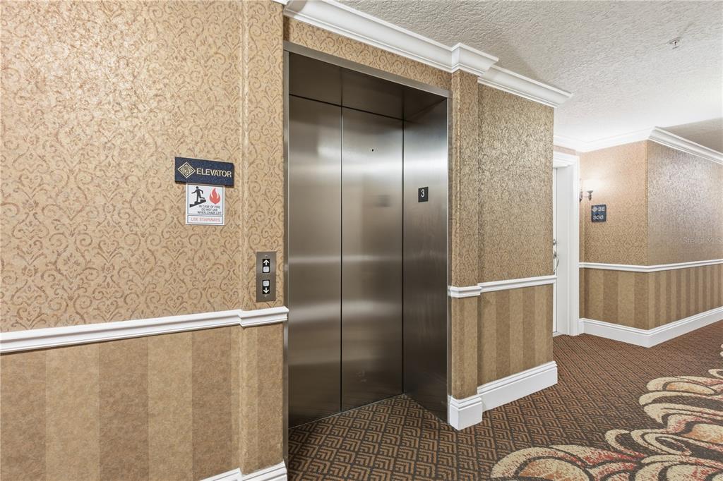A stainless steel elevator door is located in a hallway with patterned wallpaper and carpet — 700 N OSCEOLA AVENUE UNIT 305, CLEARWATER, FL