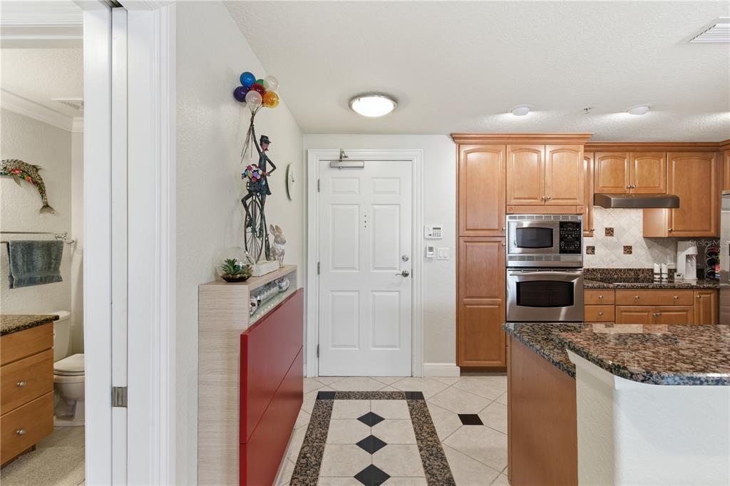 An entryway leads to a kitchen with wood cabinets, granite countertops, and tile flooring — 700 N OSCEOLA AVENUE UNIT 305, CLEARWATER, FL