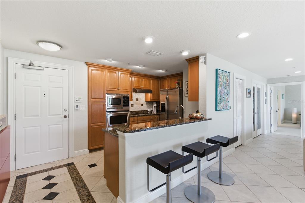 A kitchen with wood cabinets, granite countertops, and a breakfast bar with three stools — 700 N OSCEOLA AVENUE UNIT 305, CLEARWATER, FL