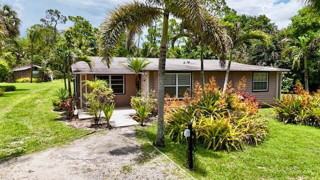 A single-story house with tan siding, a palm tree, and landscaping in the front yard — 13559 24th Court N, Loxahatchee FL 33470, LOXAHATCHEE, FL