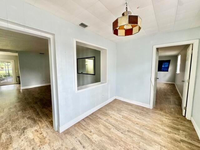 A room with light blue walls, wood-look flooring, a pass-through window, and a hanging light — 13559 24th Court N, Loxahatchee FL 33470, LOXAHATCHEE, FL