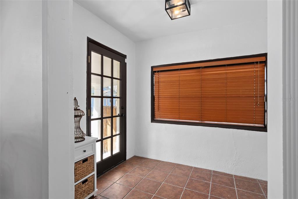 A sunroom features white walls, tile flooring, a glass-paneled door, and a large window — 225 HIBISCUS COURT, ORLANDO, FL