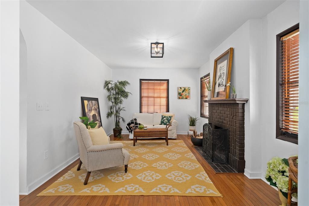 A living room features a brick fireplace, hardwood floors, and a yellow patterned area rug — 225 HIBISCUS COURT, ORLANDO, FL