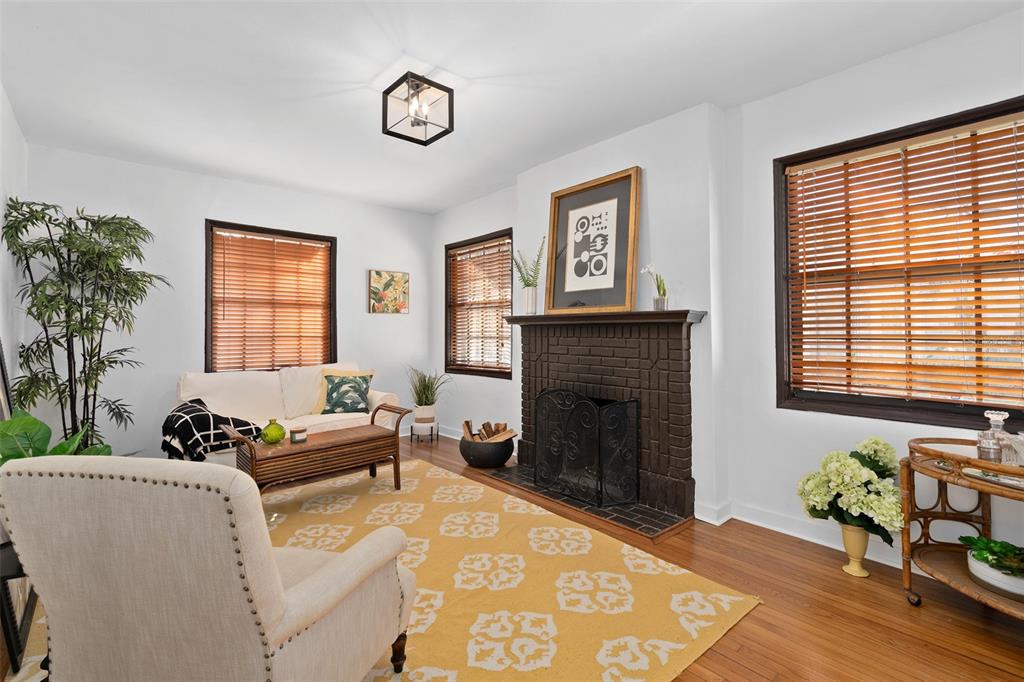A living room features a brick fireplace, hardwood floors, and a yellow patterned area rug — 225 HIBISCUS COURT, ORLANDO, FL