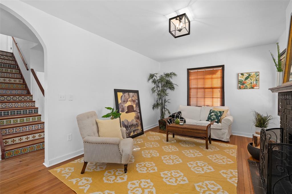 A living room with a yellow patterned rug, a staircase with decorative tiles, and furniture — 225 HIBISCUS COURT, ORLANDO, FL