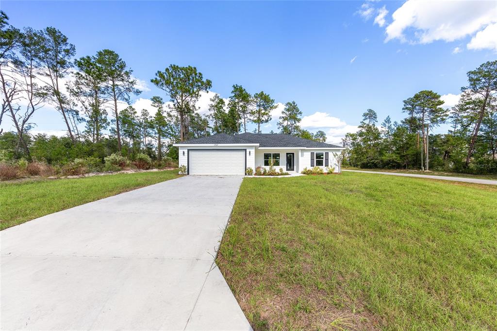 A single-story white house with a two-car garage sits on a grassy lot — 777 MARION OAKS LANE, OCALA, FL
