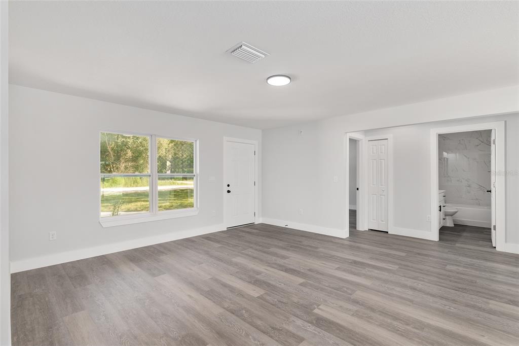 A living room features gray wood-look flooring, a gray sofa, and a wall-mounted television — 777 MARION OAKS LANE, OCALA, FL