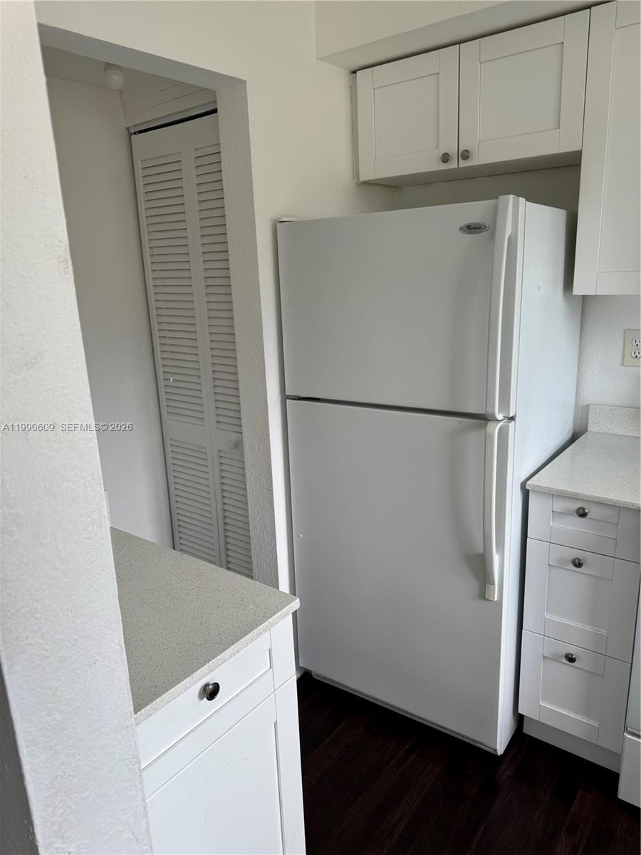 A white refrigerator is positioned between kitchen cabinets and a louvered closet door — 8301 NW 4th Ave # 8301C, Miami FL 33150, MIAMI, FL