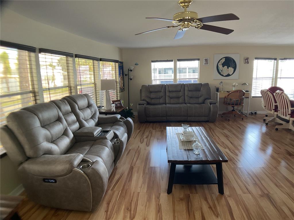 A living room features wood-look flooring, two gray reclining sofas, and a wooden coffee table — 2100 KINGS HIGHWAY UNIT 98, PORT CHARLOTTE, FL