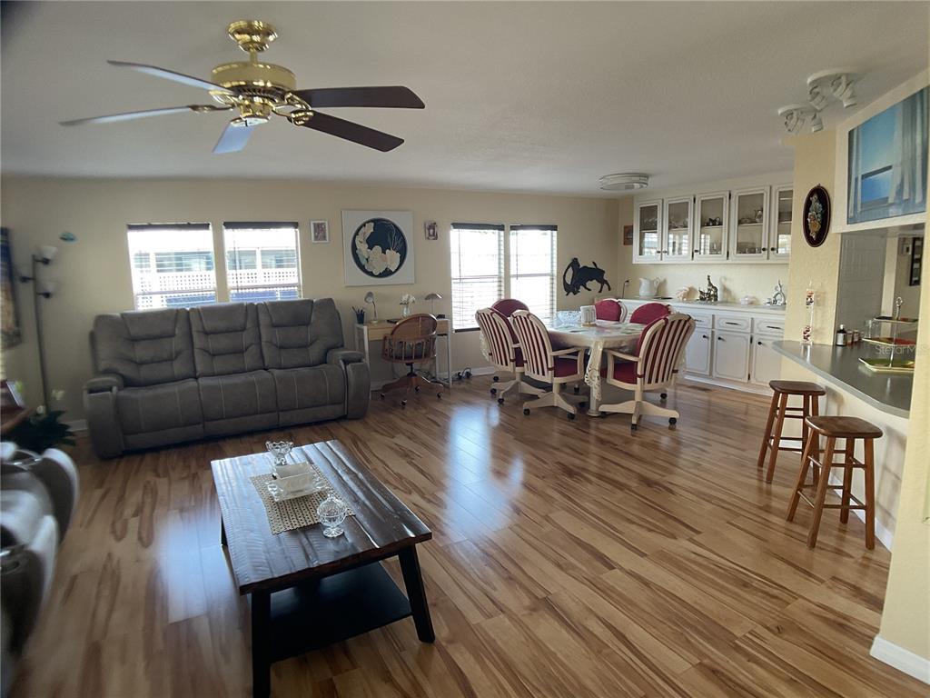 A living and dining area features wood-look flooring, a ceiling fan, and white cabinetry — 2100 KINGS HIGHWAY UNIT 98, PORT CHARLOTTE, FL