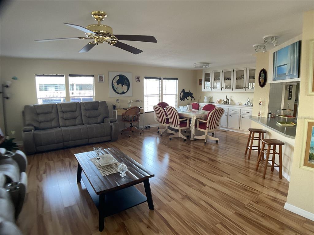 An open-concept living and dining area features wood-look flooring, a ceiling fan, and white cabinetry — 2100 KINGS HIGHWAY UNIT 98, PORT CHARLOTTE, FL