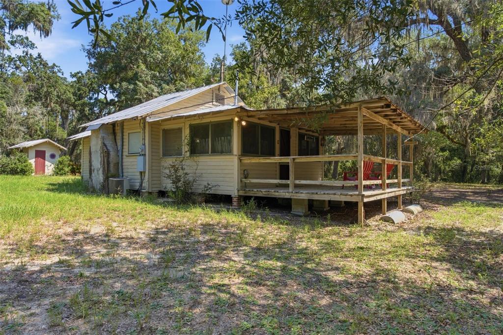 A small, light-colored wooden cottage with a front porch sits on a grassy, wooded lot — 0 FOREST 02, #1, SE 150TH STREET, UMATILLA, FL