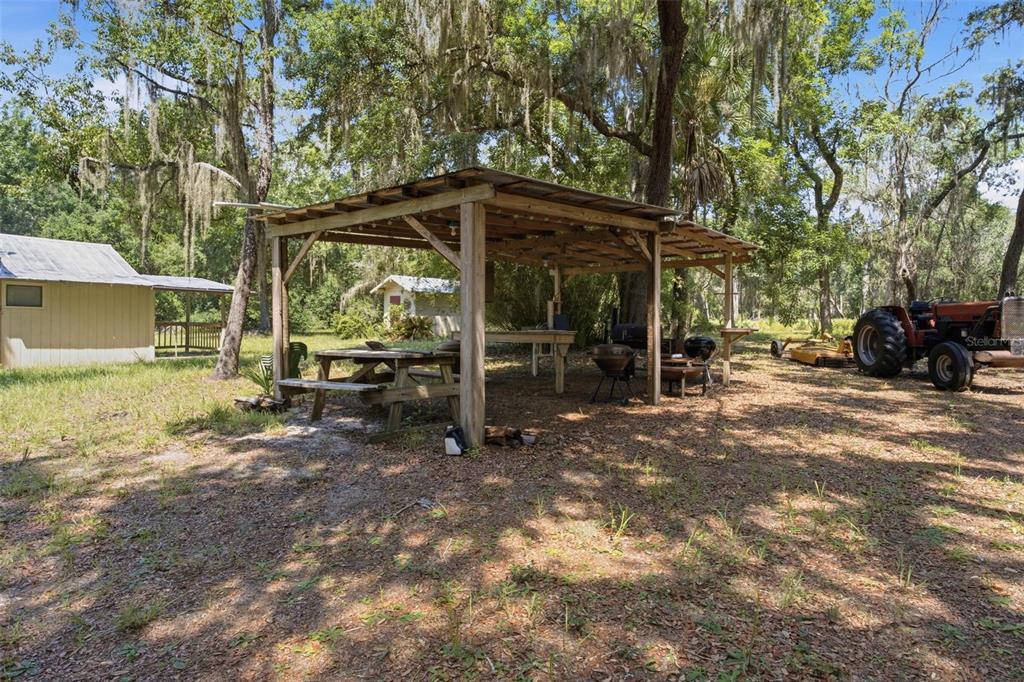 An outdoor wooden pavilion with a picnic table and grill sits in a wooded yard — 0 FOREST 02, #1, SE 150TH STREET, UMATILLA, FL