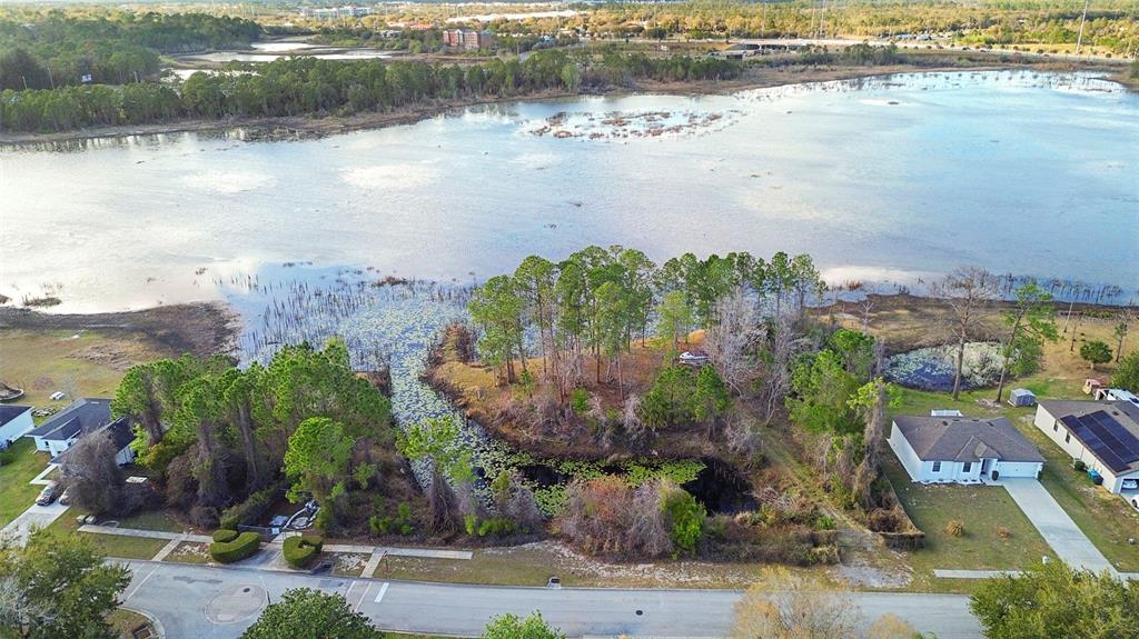 An aerial view shows a residential lot with trees and a pond near a lake — 458 HAVERSHAM ROAD, DELTONA, FL