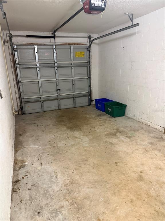 An empty garage features a concrete floor, white block walls, and a sectional overhead door — 49 PROVIDENCE LANE UNIT B, PALM COAST, FL