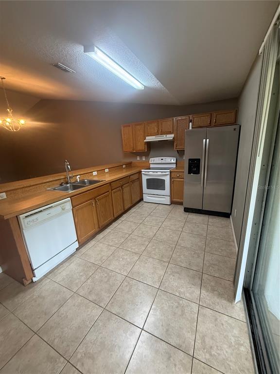 A kitchen features oak cabinets, laminate countertops, a white dishwasher, and a stainless steel refrigerator — 49 PROVIDENCE LANE UNIT B, PALM COAST, FL