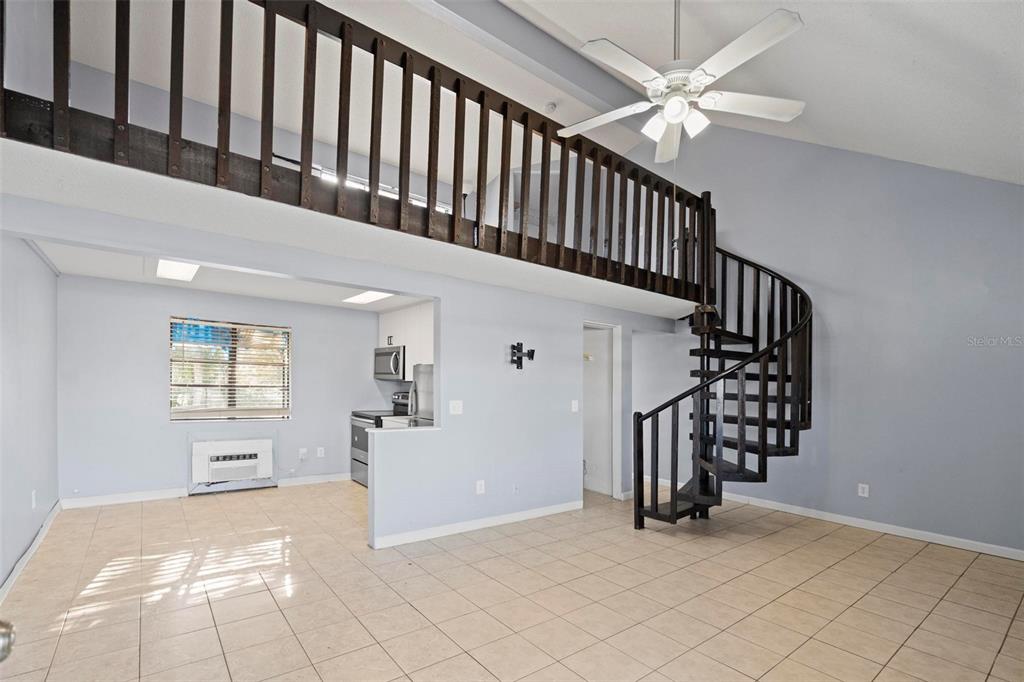 A living room features tile flooring, a spiral staircase, and a loft with a wooden railing — 2142 BRADFORD STREET UNIT 323, CLEARWATER, FL