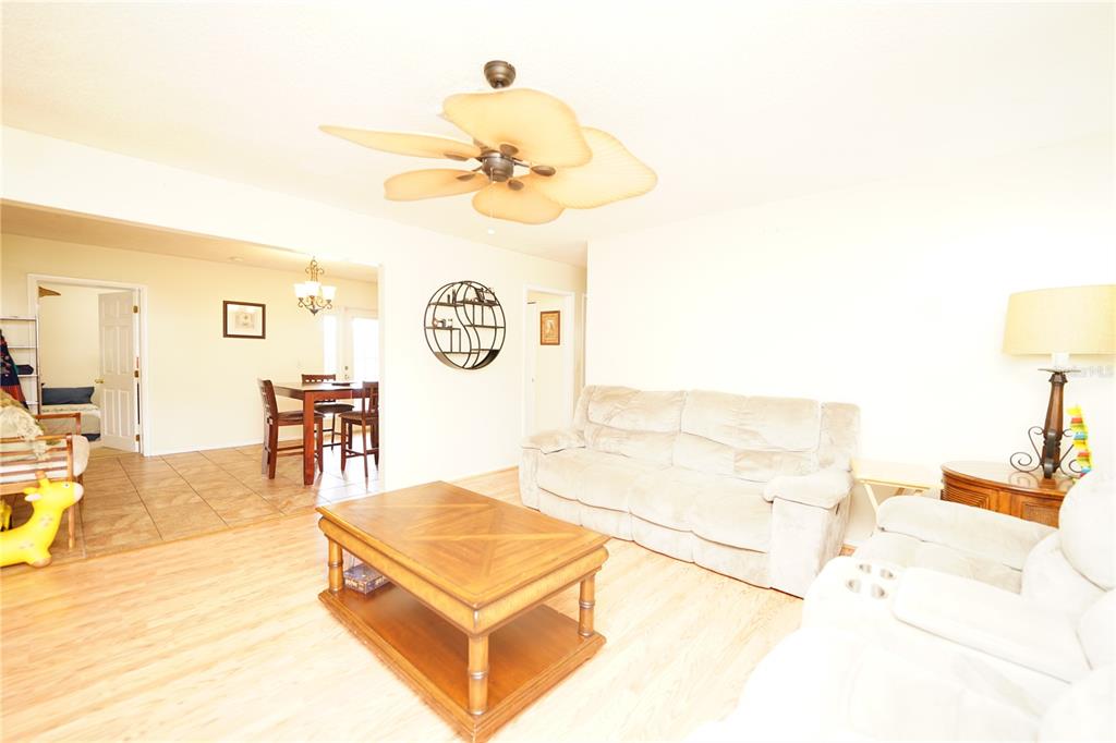 A living room with light wood flooring, a beige sofa, and a ceiling fan — 8300 75TH AVENUE, SEMINOLE, FL
