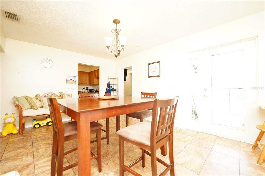 A dining area features a wooden table, chairs, tile flooring, and a chandelier — 8300 75TH AVENUE, SEMINOLE, FL