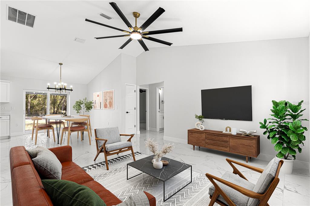 A living room with a vaulted ceiling, ceiling fan, marble-look floors, and a dining area — 10325 SE 125TH LANE, BELLEVIEW, FL