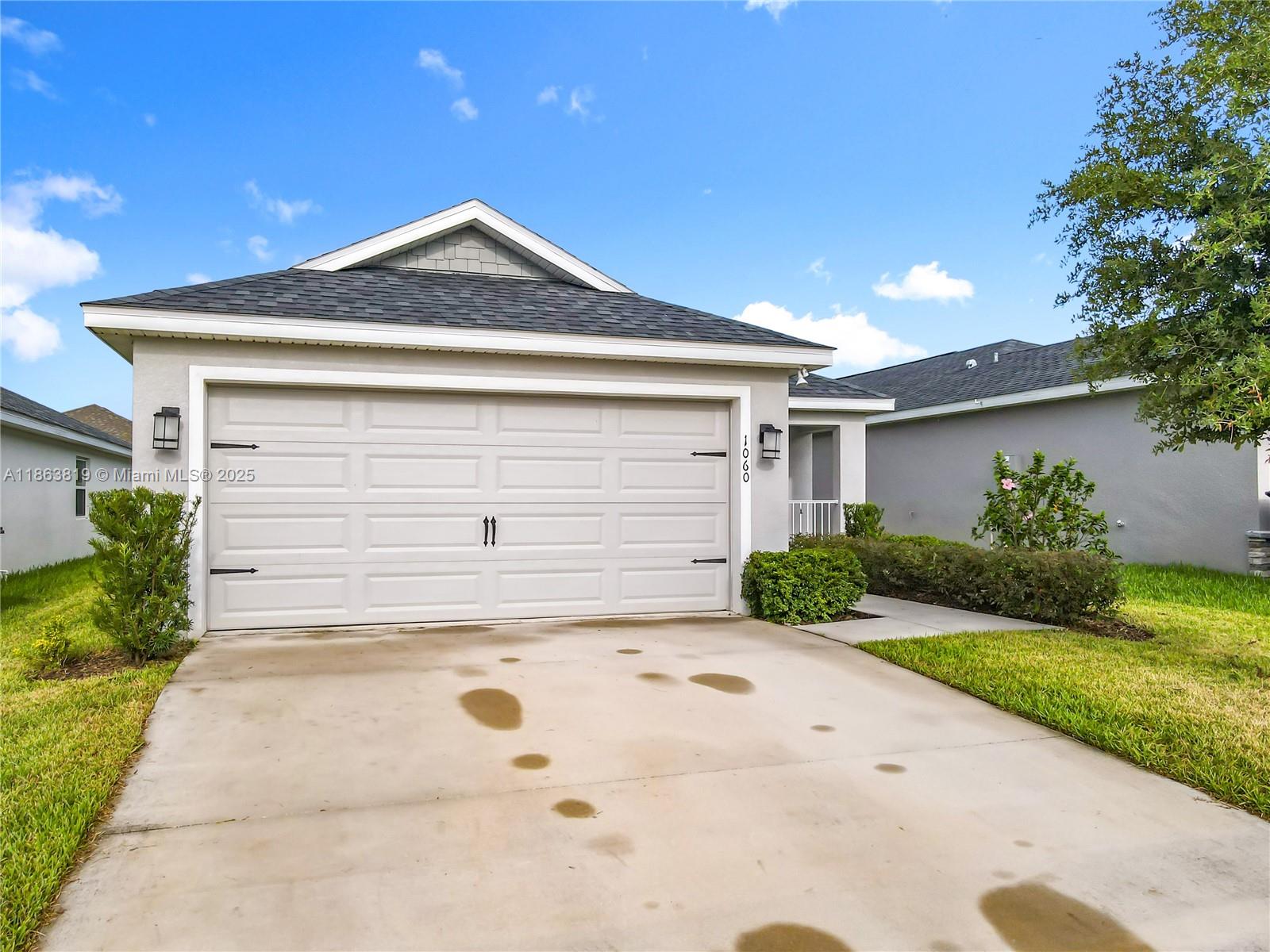 A single-story house features a two-car garage, a concrete driveway, and a small front lawn — 1060 Cascade Drive, Davenport FL 33837, DAVENPORT, FL