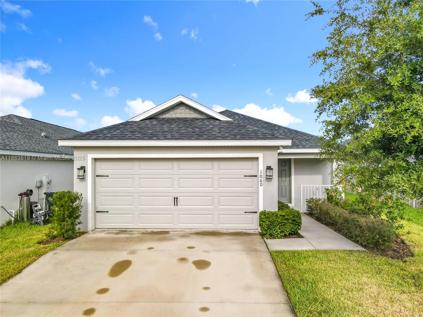 A single-story house features a light gray exterior, a two-car garage, and a concrete driveway — 1060 Cascade Drive, Davenport FL 33837, DAVENPORT, FL