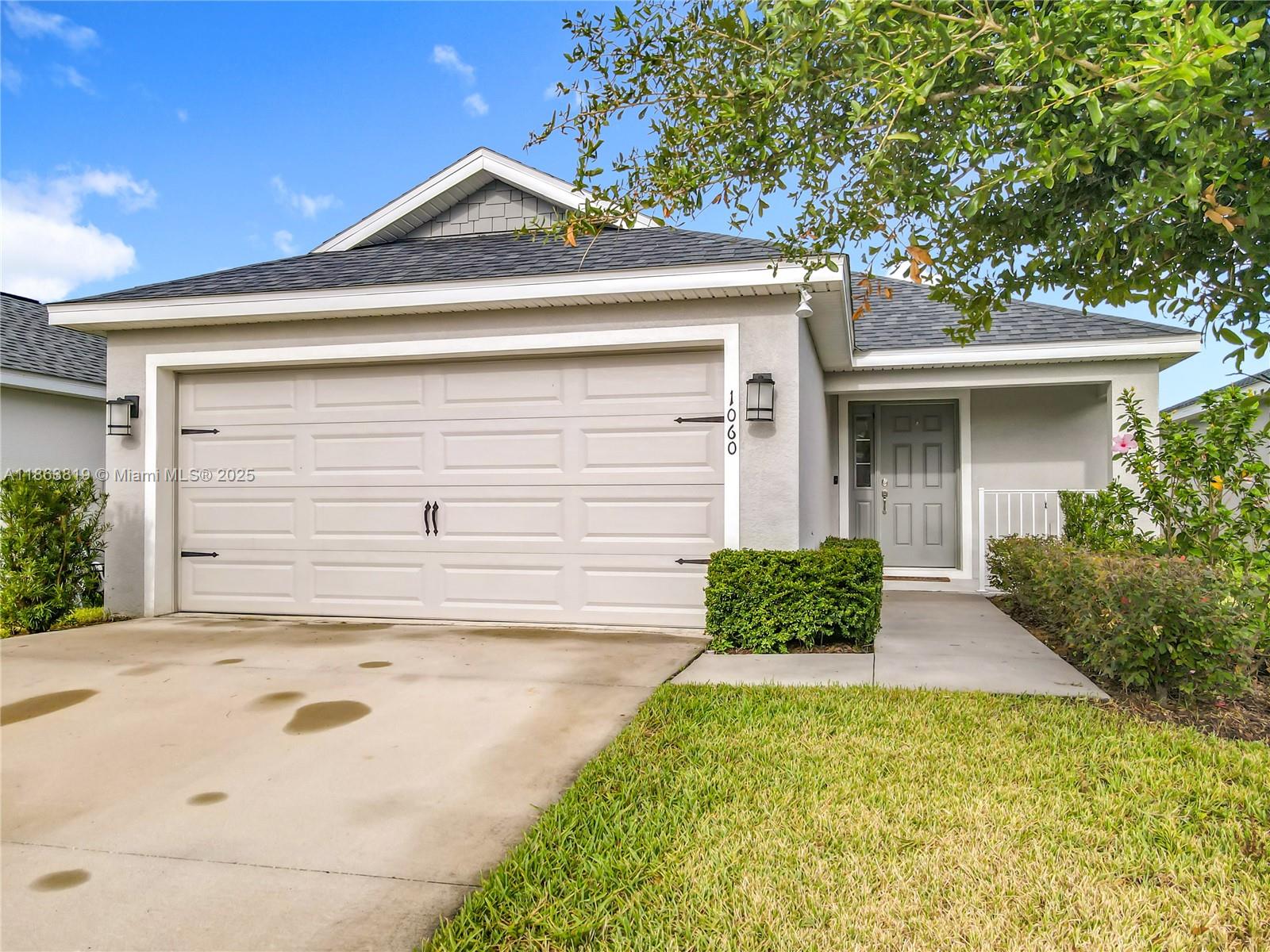 A single-story house features a two-car garage, a gray front door, and a concrete driveway — 1060 Cascade Drive, Davenport FL 33837, DAVENPORT, FL