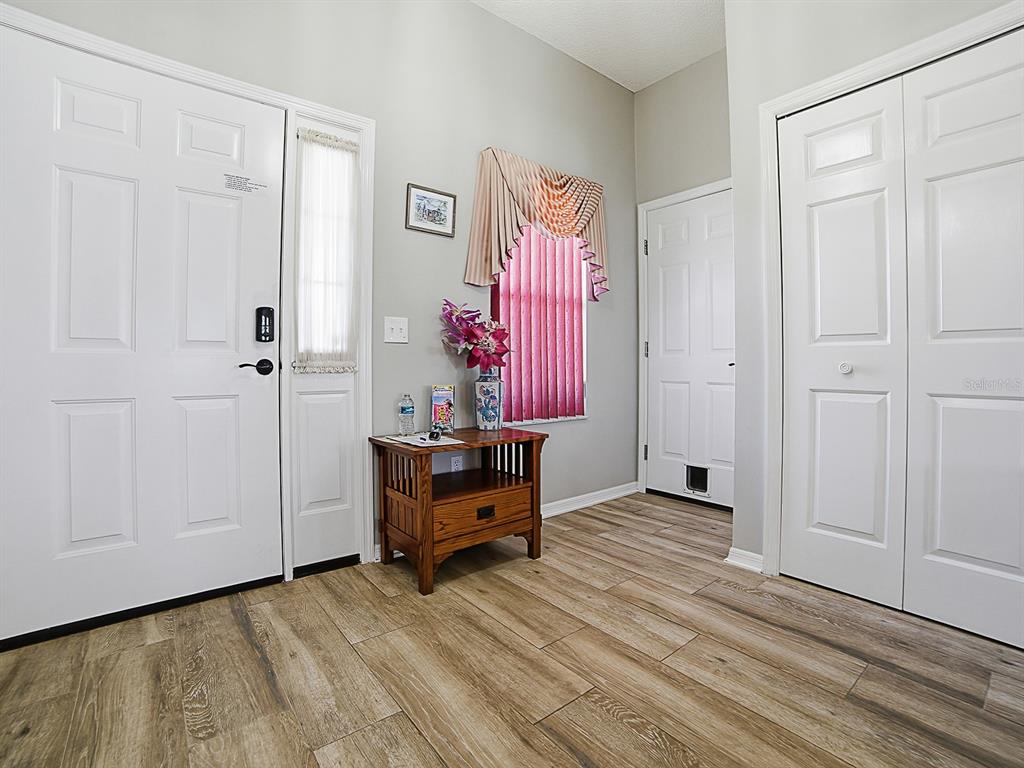 An entryway features wood-look tile flooring, a white front door, and a small wooden table — 820 CORTEZ AVENUE, LADY LAKE, FL