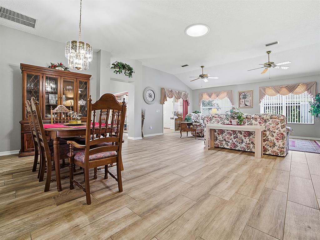 A dining area and living room feature wood-look tile flooring and vaulted ceilings — 820 CORTEZ AVENUE, LADY LAKE, FL