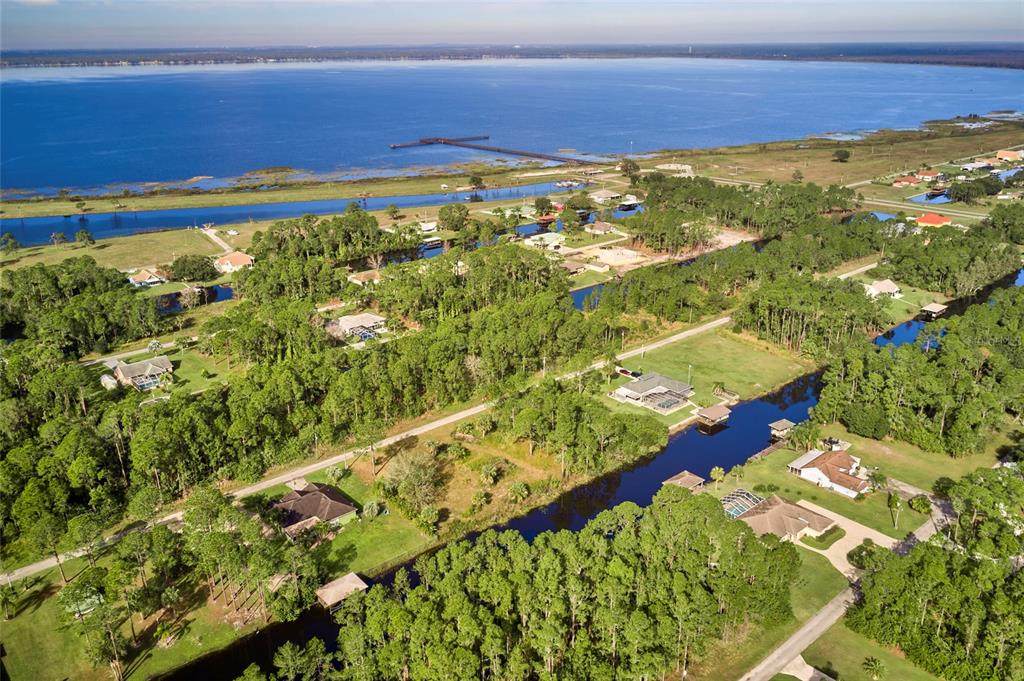 An aerial view shows houses nestled among trees along a canal leading to a lake — OLEANDER DRIVE, INDIAN LAKE ESTATES, FL