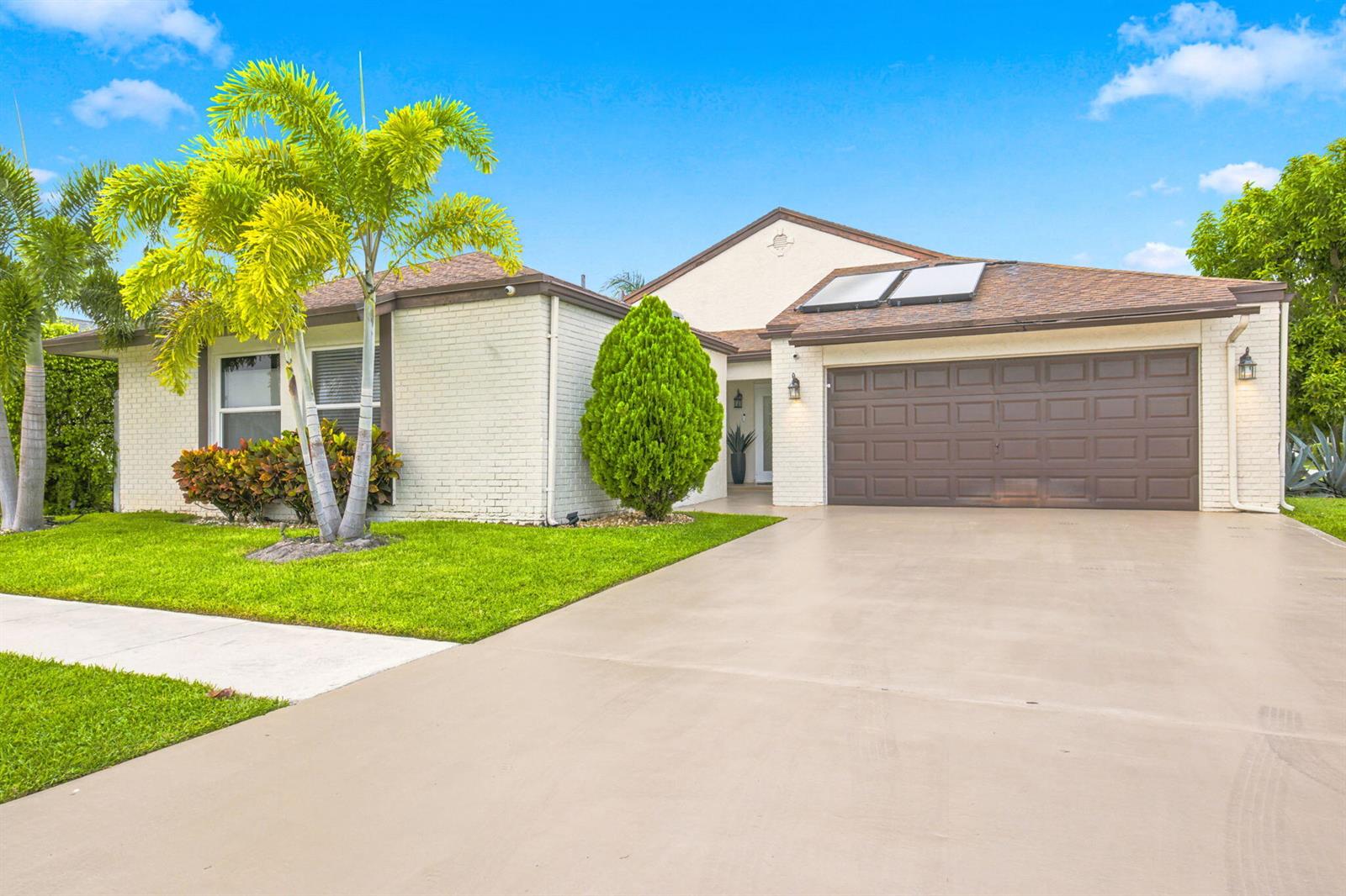 A single-story house with a white brick exterior, brown garage door, and a palm tree — 11455 Whisper Sound Drive, Boca Raton FL 33428, BOCA RATON, FL