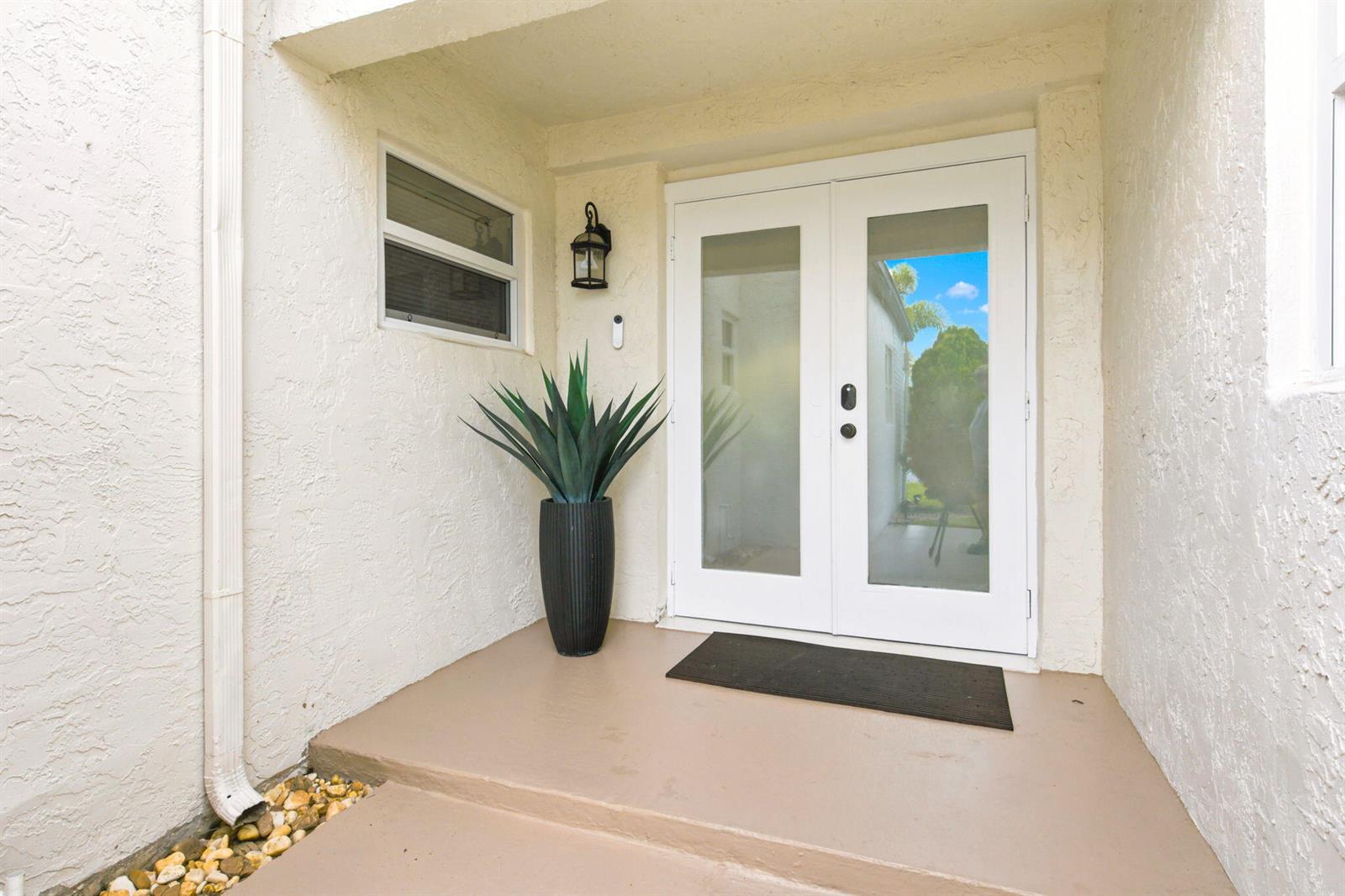 A white double door entrance with frosted glass panels sits on a covered concrete porch — 11455 Whisper Sound Drive, Boca Raton FL 33428, BOCA RATON, FL