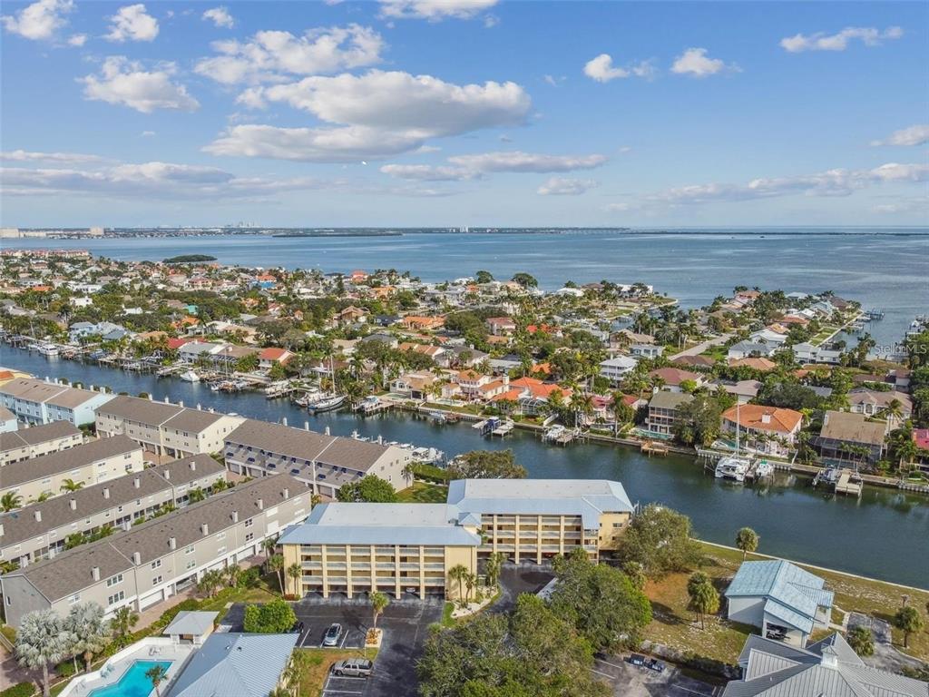 An aerial view of a multi-story apartment building situated near a canal and the ocean — 1125 PINELLAS BAYWAY S UNIT 302, TIERRA VERDE, FL
