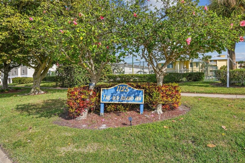 A blue sign for The Old Island Inn stands in a grassy yard with trees — 1125 PINELLAS BAYWAY S UNIT 302, TIERRA VERDE, FL