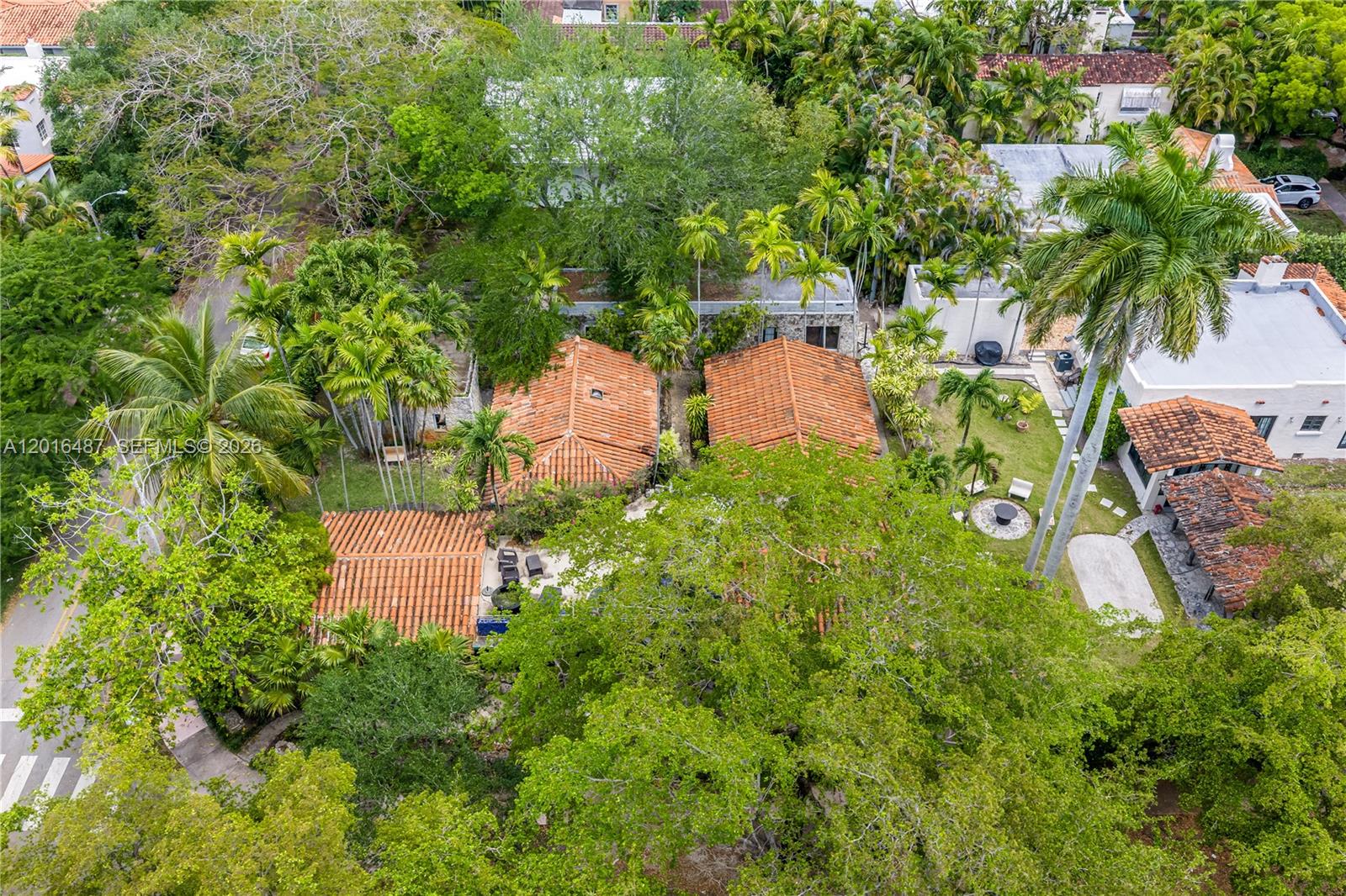 An aerial view shows several buildings with terracotta tile roofs nestled among lush tropical trees — 1301 Milan Ave # 3, Coral Gables FL 33134, CORAL GABLES, FL