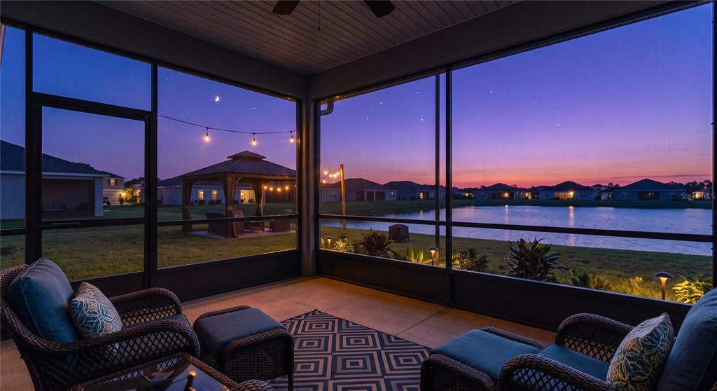 A screened-in patio overlooks a lake and a gazebo at sunset — 410 FAIRFIELD DRIVE, SANFORD, FL