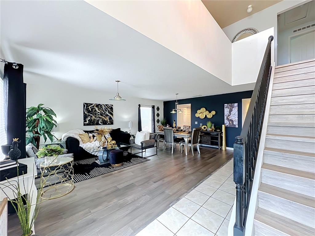 An open-concept living and dining area features dark wood flooring, a staircase, and blue accents — 410 FAIRFIELD DRIVE, SANFORD, FL