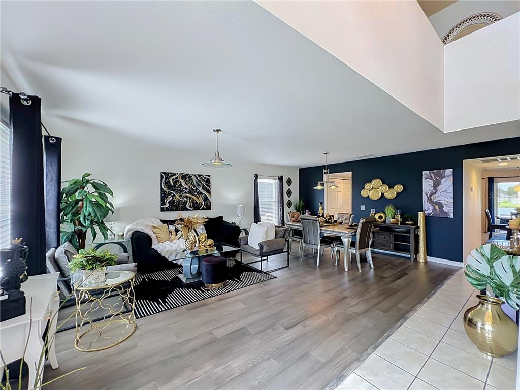 An open-concept living and dining area features dark blue accent walls and wood flooring — 410 FAIRFIELD DRIVE, SANFORD, FL