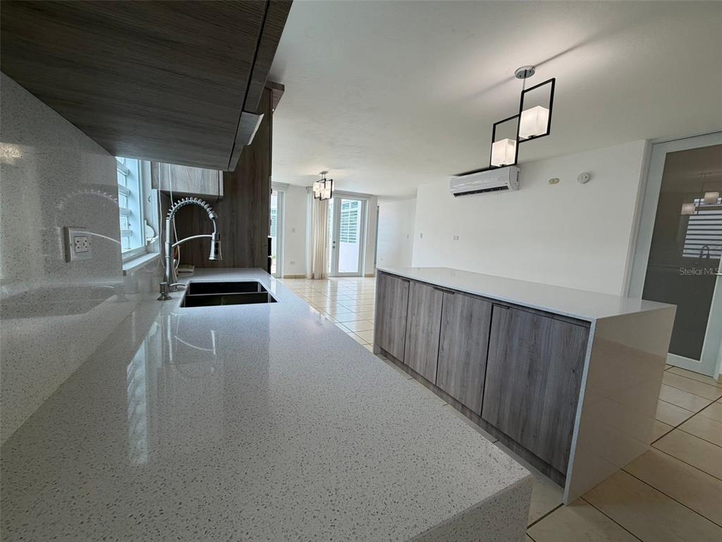 A modern kitchen features white quartz countertops, wood-grain cabinetry, and a pendant light fixture — A-70 Calle Persia PALACIO IMPERIAL, TOA ALTA, PR