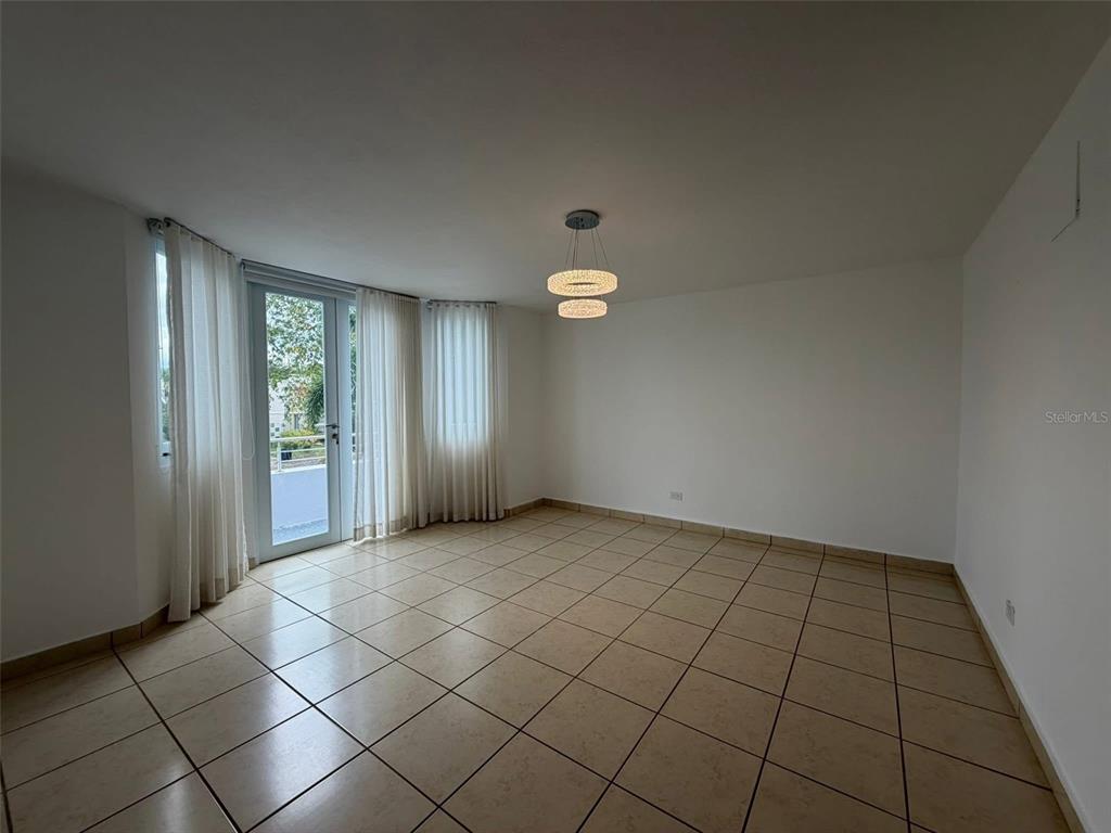 An empty room features beige tile flooring, white walls, a modern light fixture, and glass doors — A-70 Calle Persia PALACIO IMPERIAL, TOA ALTA, PR